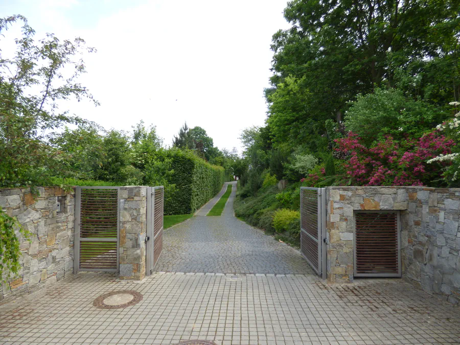 Otevřená brána kombinující kámen, nerezovou ocel a tropické dřevo