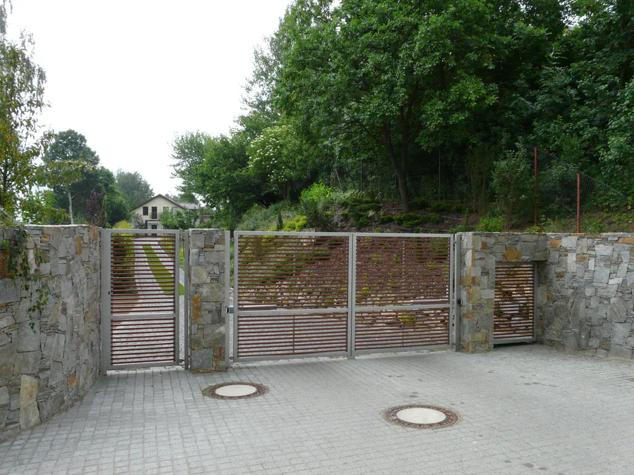 Zavřená brána s kamennými sloupky, nerezovým rámem a dřevěnou výplní